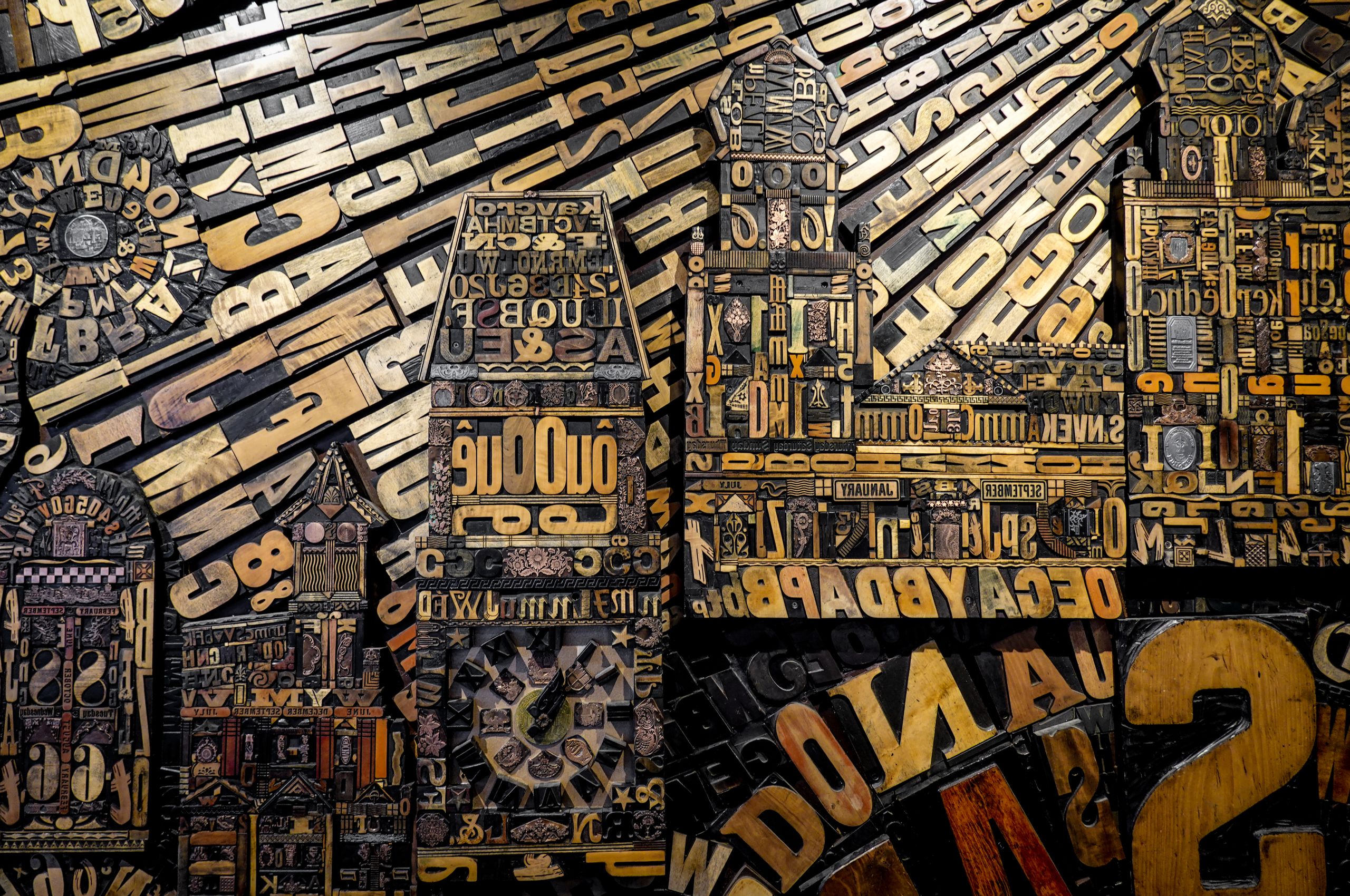 A complex display of carved wooden letters and numbers creating a unique mural.